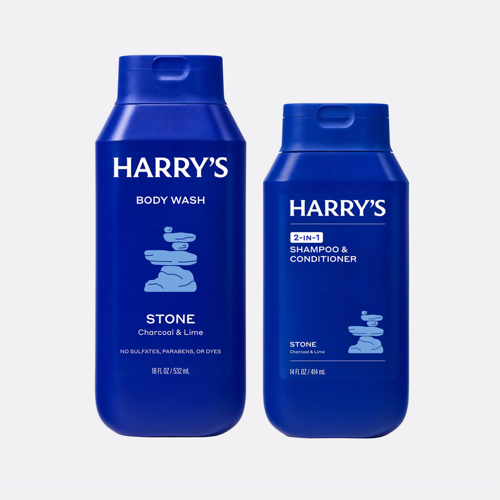 Two blue bottles of Harry's Stone body wash and shampoo & conditioner on a white background