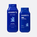 Two blue bottles of Harry's Stone body wash and shampoo & conditioner on a white background