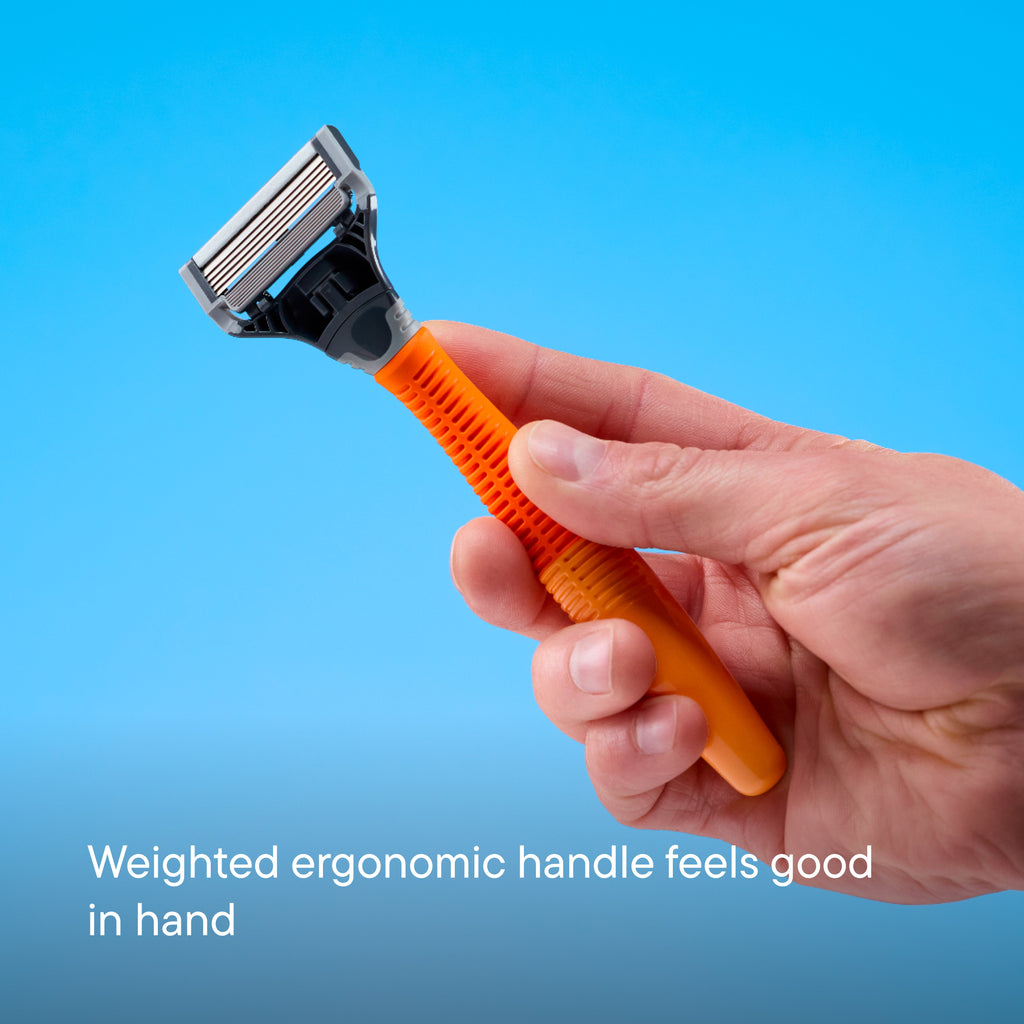A hand holding a modern three-blade razor with an orange ergonomic handle and a silver metal head, set against a solid blue background with the text 'Weighted ergonomic handle feels good in hand'.
