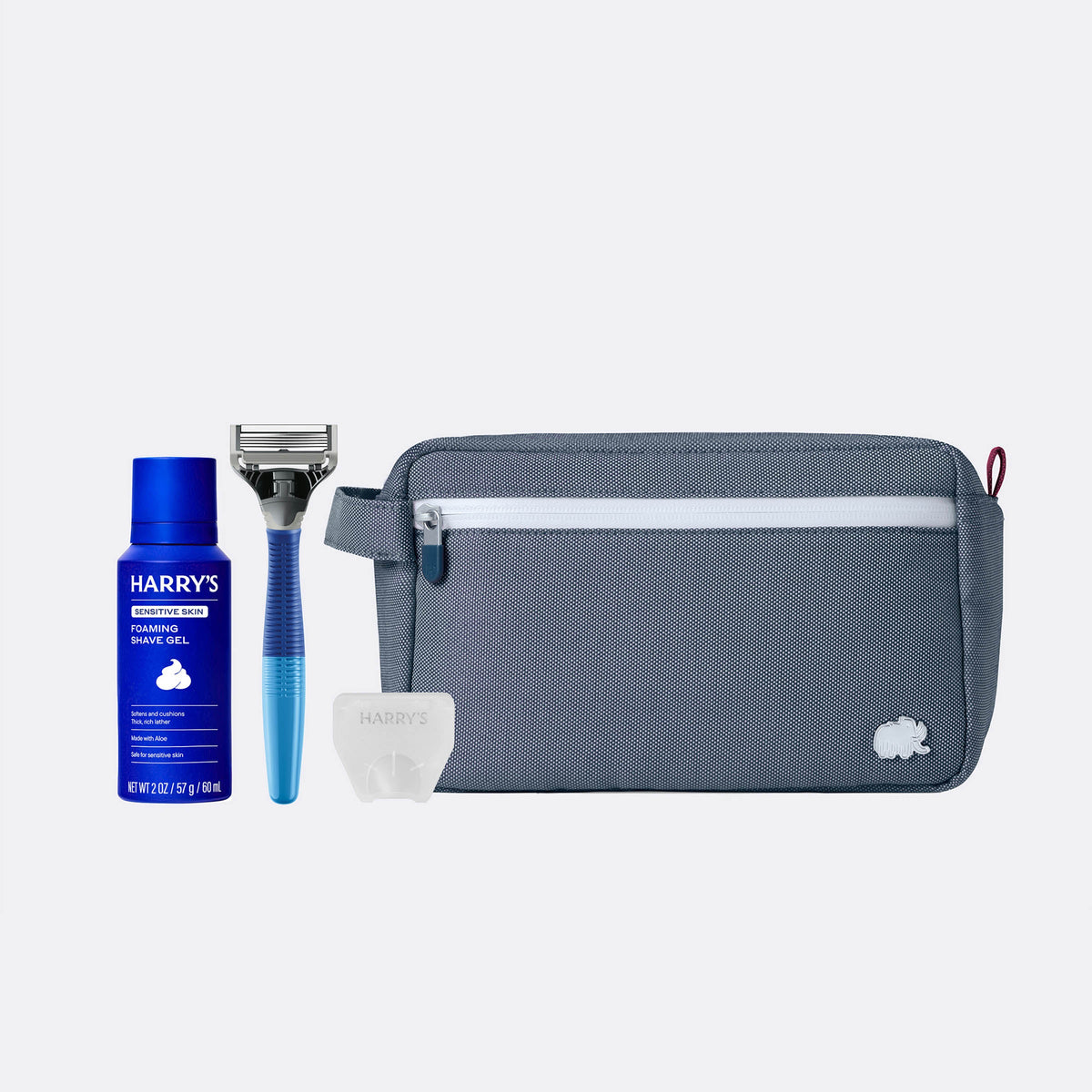 Set of grooming products including a blue bottle, razor, and gray pouch on a white background