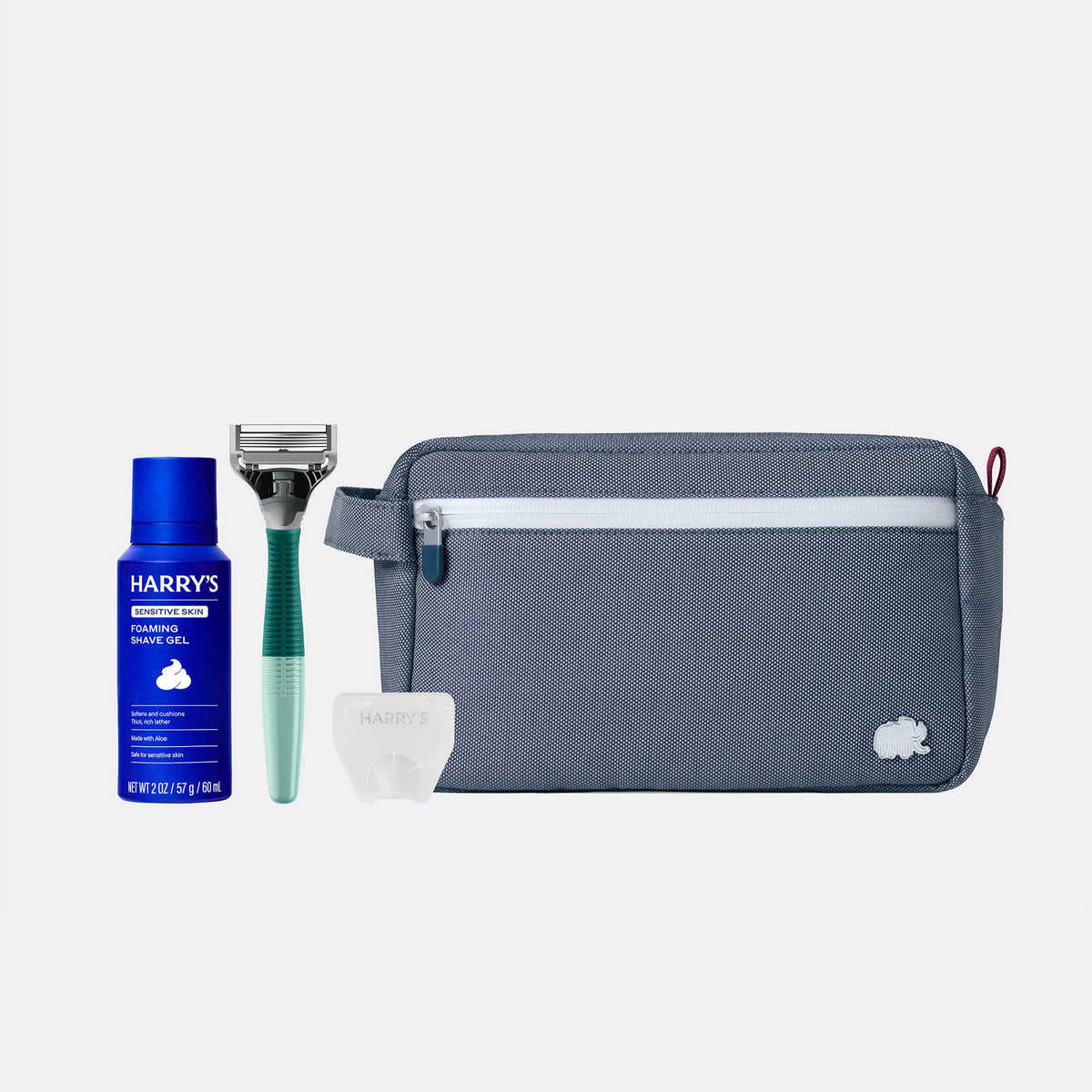 Set of grooming products including a blue bottle, razor, and gray pouch on a white background