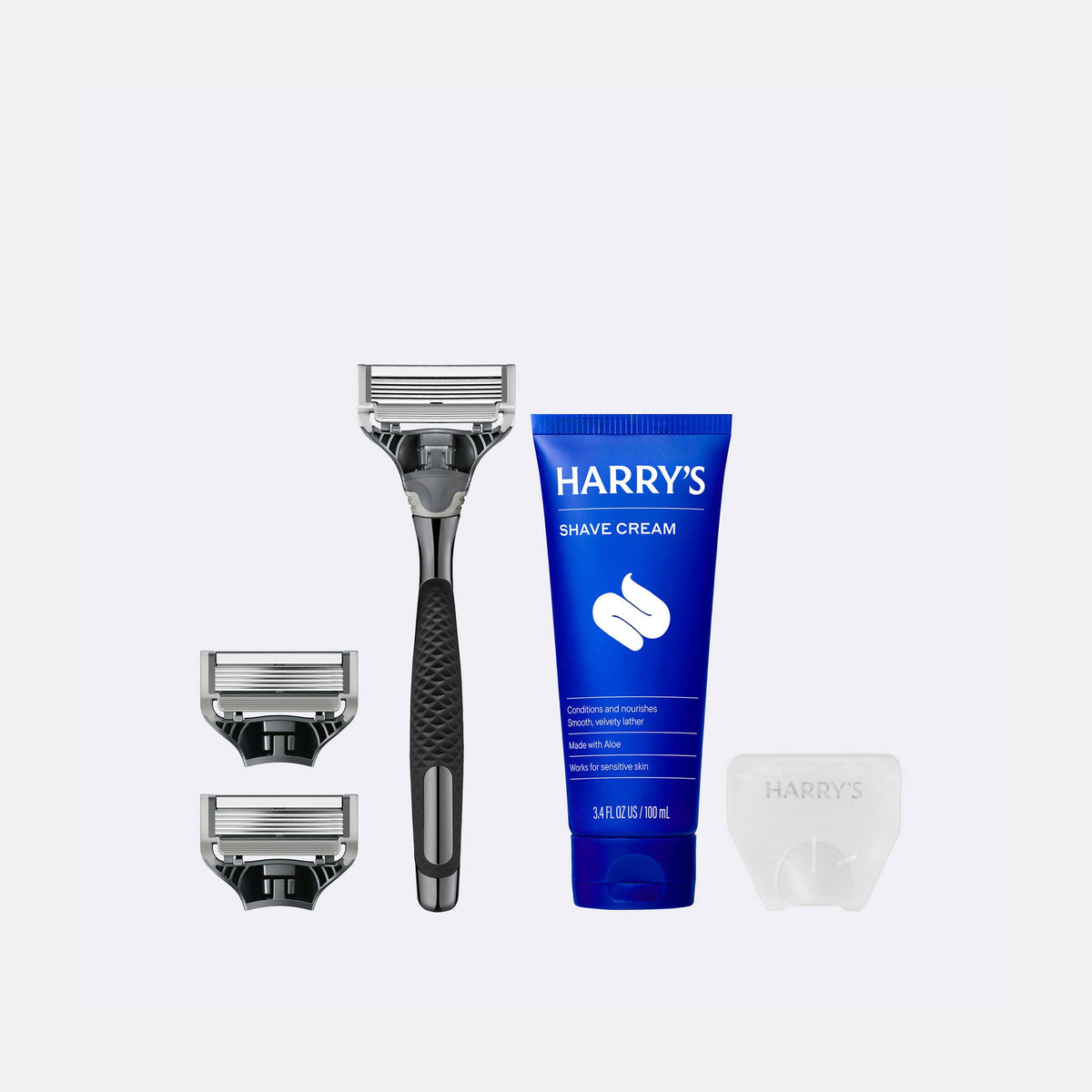 Harry's shaving kit with razor, razor heads, and shave cream on a white background