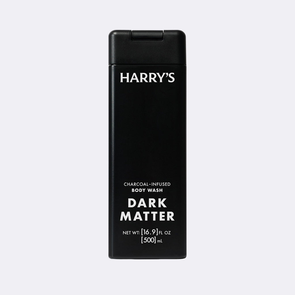 A tall black rectangular bottle of Harry's Dark Matter Charcoal-Infused Body Wash, featuring white text on a light gray background.