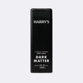 A tall black rectangular bottle of Harry's Dark Matter Charcoal-Infused Body Wash, featuring white text on a light gray background.