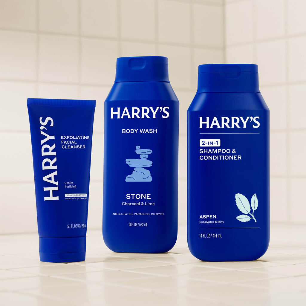 Three blue bottles of Harry's grooming products on a light background