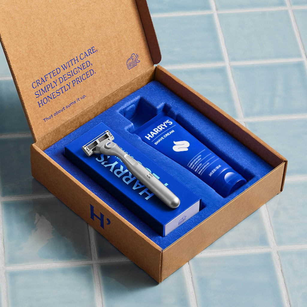 Harvey's razor and shaving cream set in a branded box on a tiled floor.