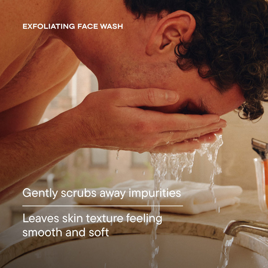 Man washing his face with water in a bathroom setting, using exfoliating face wash.