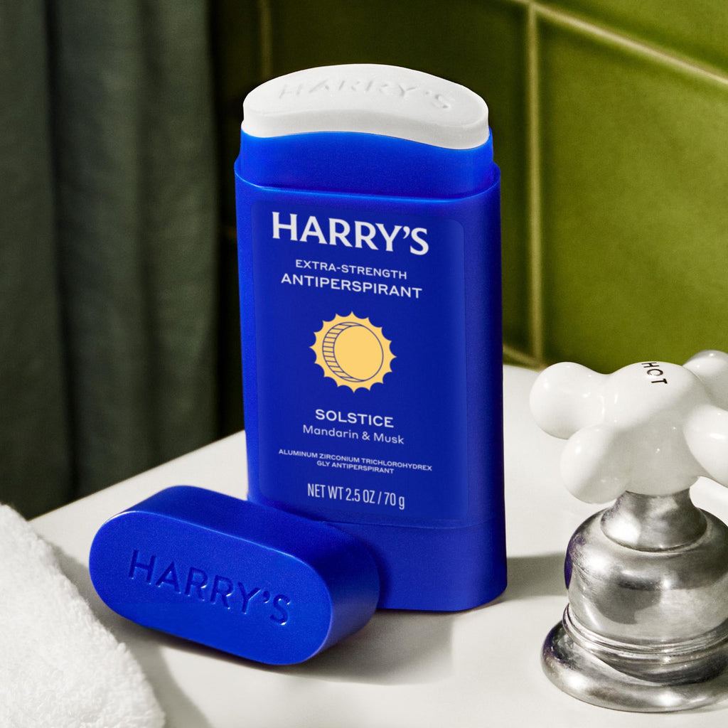 Blue antiperspirant stick with white cap on a bathroom counter, featuring 'Harry's' branding.