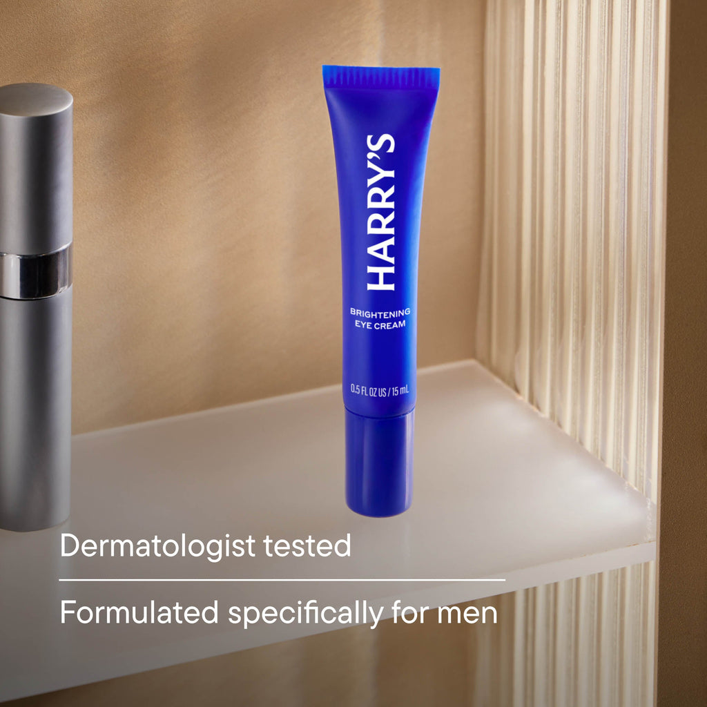 Blue tube of Harry's eye cream on a bathroom shelf with text about dermatologist testing and men-specific formulation.