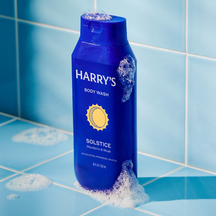 Blue bottle of Harry's body wash on a blue tiled bathroom self
