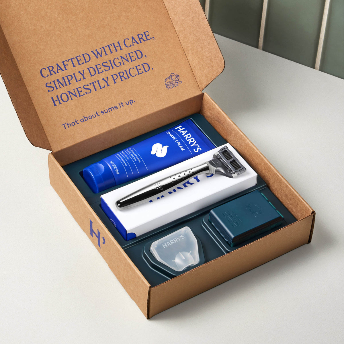Harry's grooming kit with razor and products in a cardboard box on a white surface.