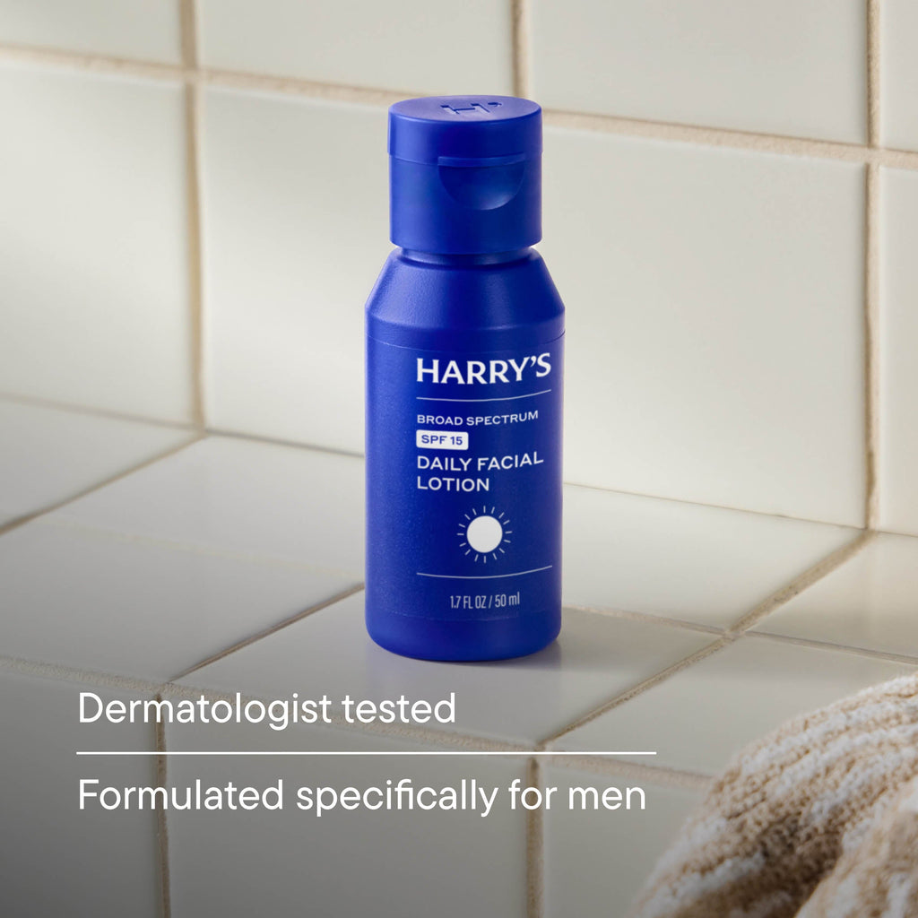 Blue bottle of Harry's daily facial lotion on a tiled bathroom wall.