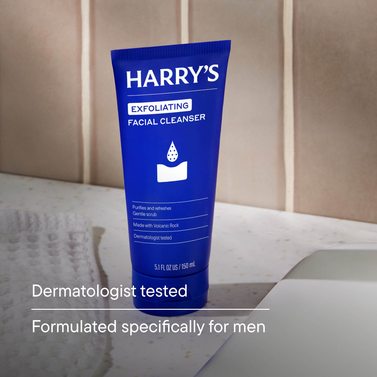 Blue tube of Harry's exfoliating facial cleanser on a bathroom counter.