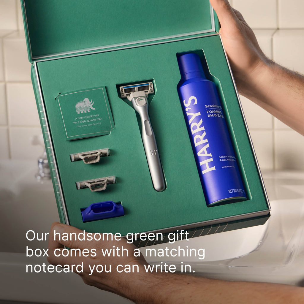 Green gift box with shaving products including a blue bottle labeled 'HARRY'S' and a silver razor.