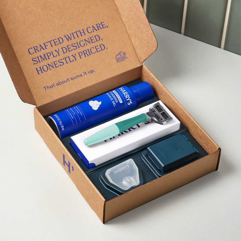 Open cardboard box containing a Harry's grooming kit with a blue tube and green and white razor.