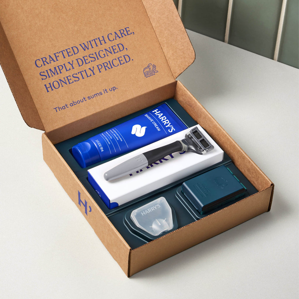 Harry's grooming kit with razor and products in a cardboard box on a white surface.