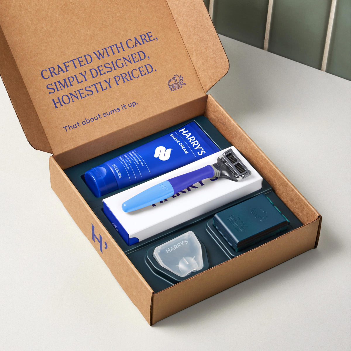 Harry's grooming kit with razor and products in a cardboard box on a white surface.