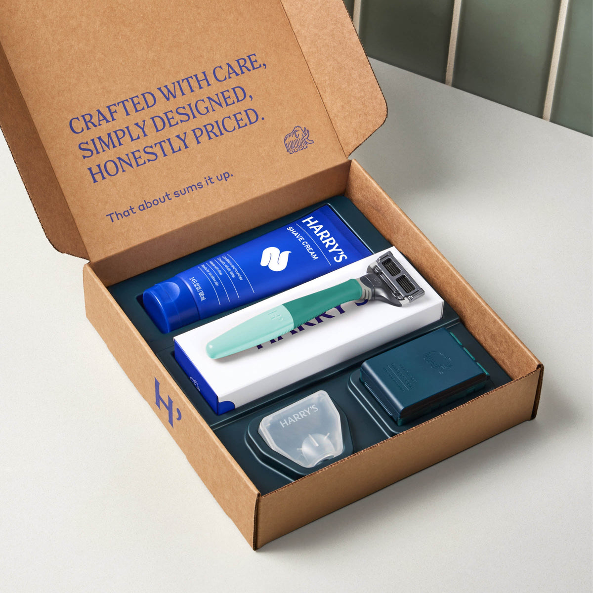 Harry's grooming kit with a razor and other items in an open cardboard box.