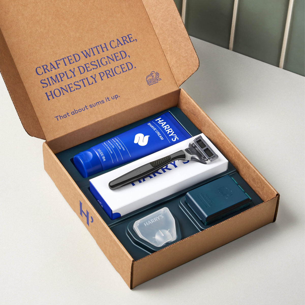 Harry's grooming kit with razor and products in a cardboard box on a white surface.