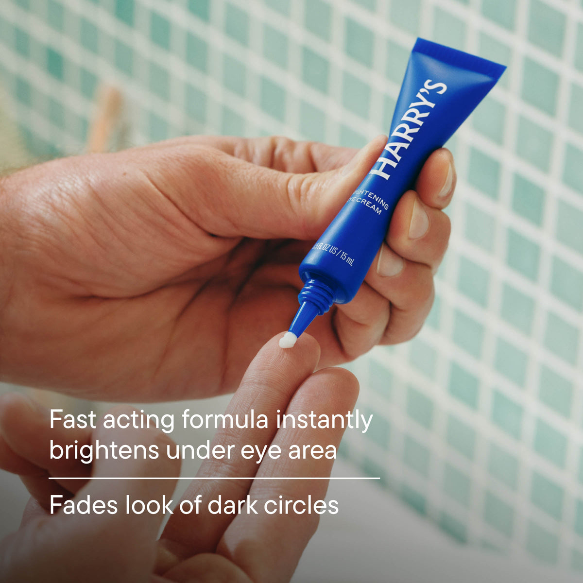 Hand holding a blue tube labeled 'HARRY'S' with text about eye cream benefits.