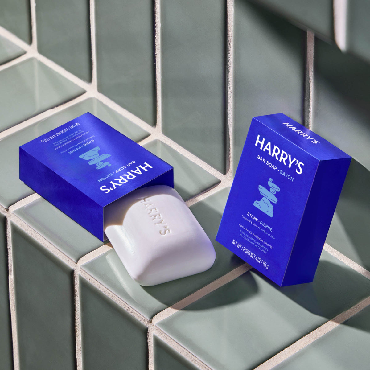Two bars of Harry's soap with their packaging on a tiled surface