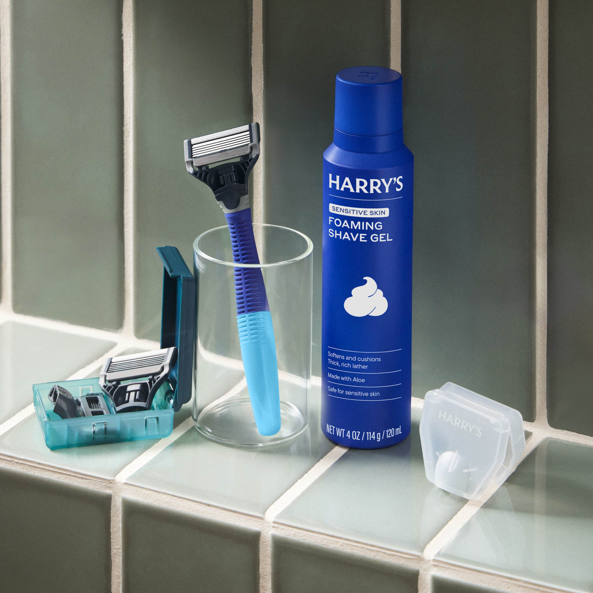 Harry's shaving products including a blue bottle of foaming shave gel, a razor, and razors in a holder on a bathroom counter.