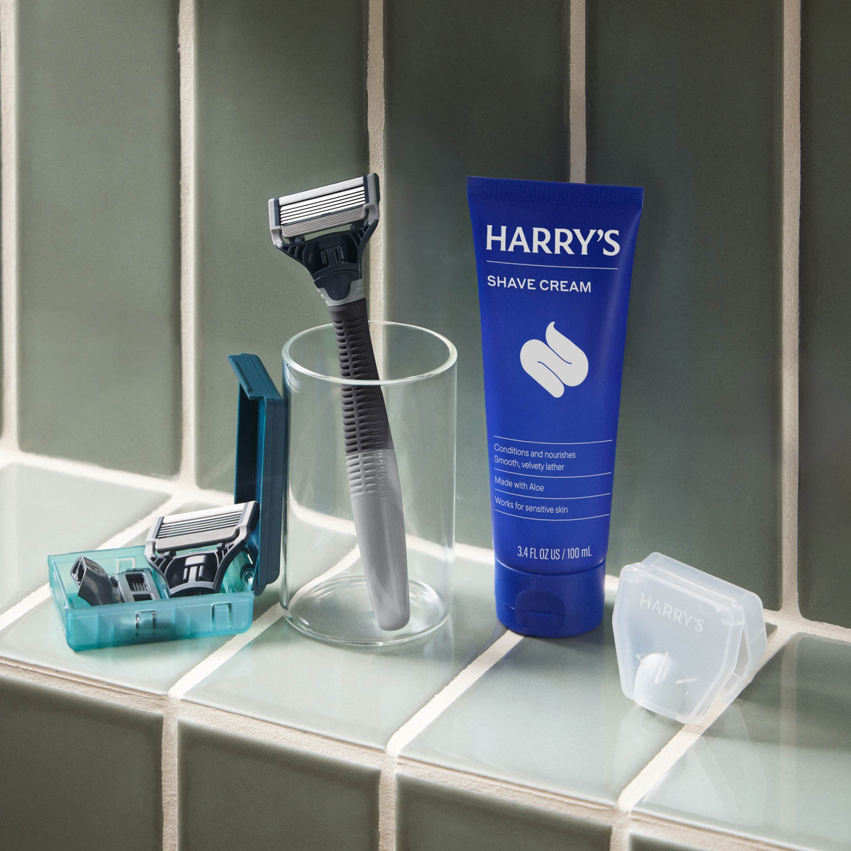 Shaving kit with razor, razors in a container, and Harry's shave cream on a bathroom counter.