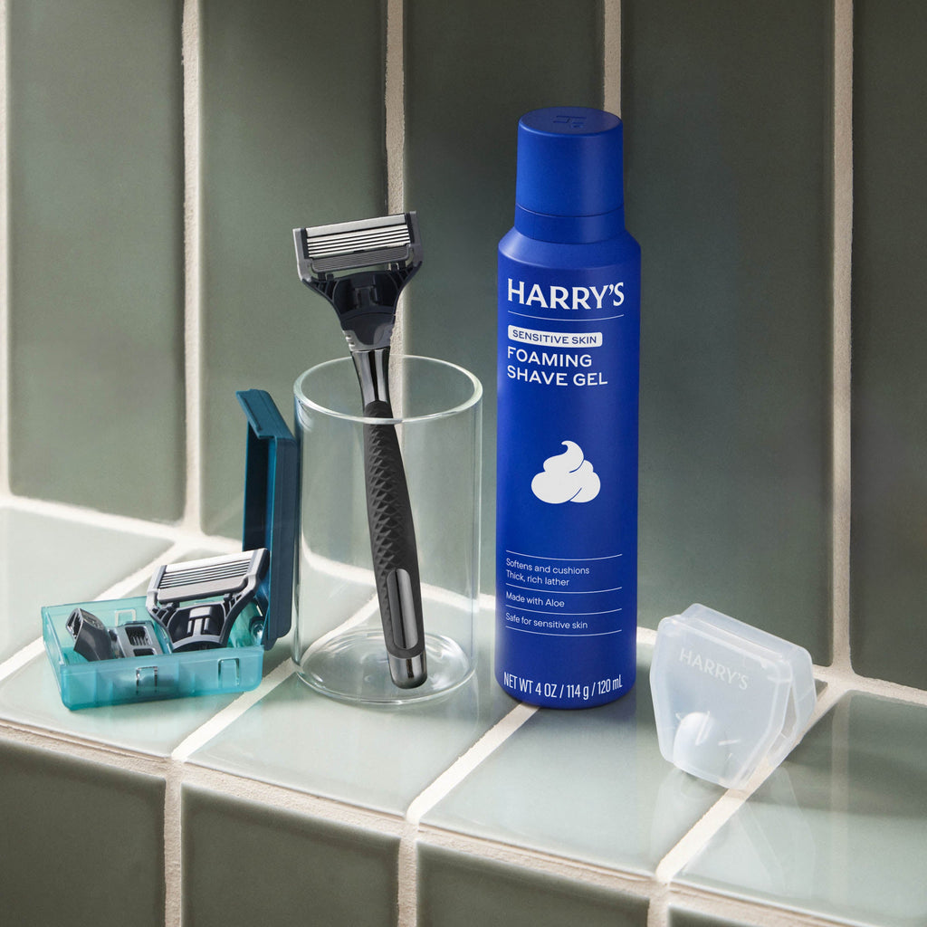 Harry's shaving products including a bottle of foaming shave gel, razor, and razors on a bathroom counter.