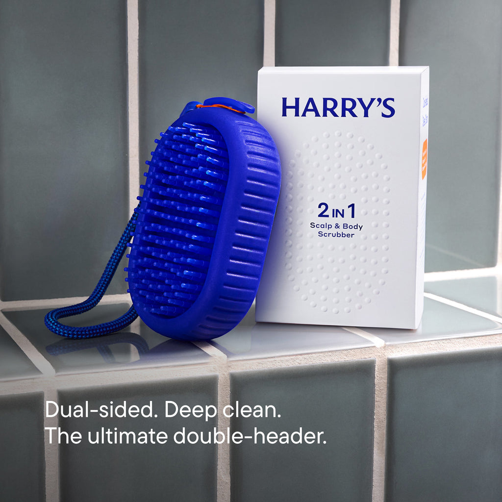 Blue scalp scrubber and 'HARRY'S' packaging on a tiled surface