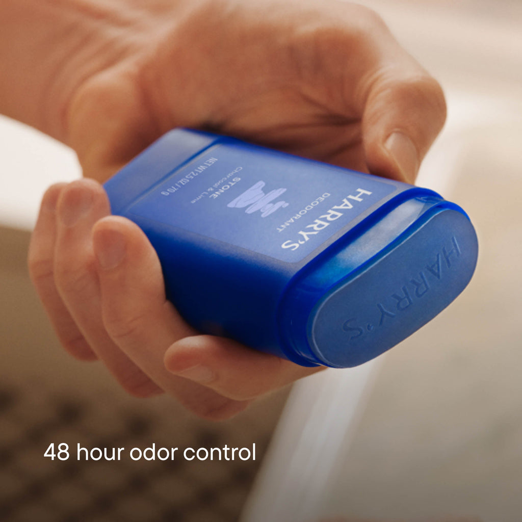 Hand holding a blue deodorant container labeled 'HARRY'S' with '48 hour odor control' text.