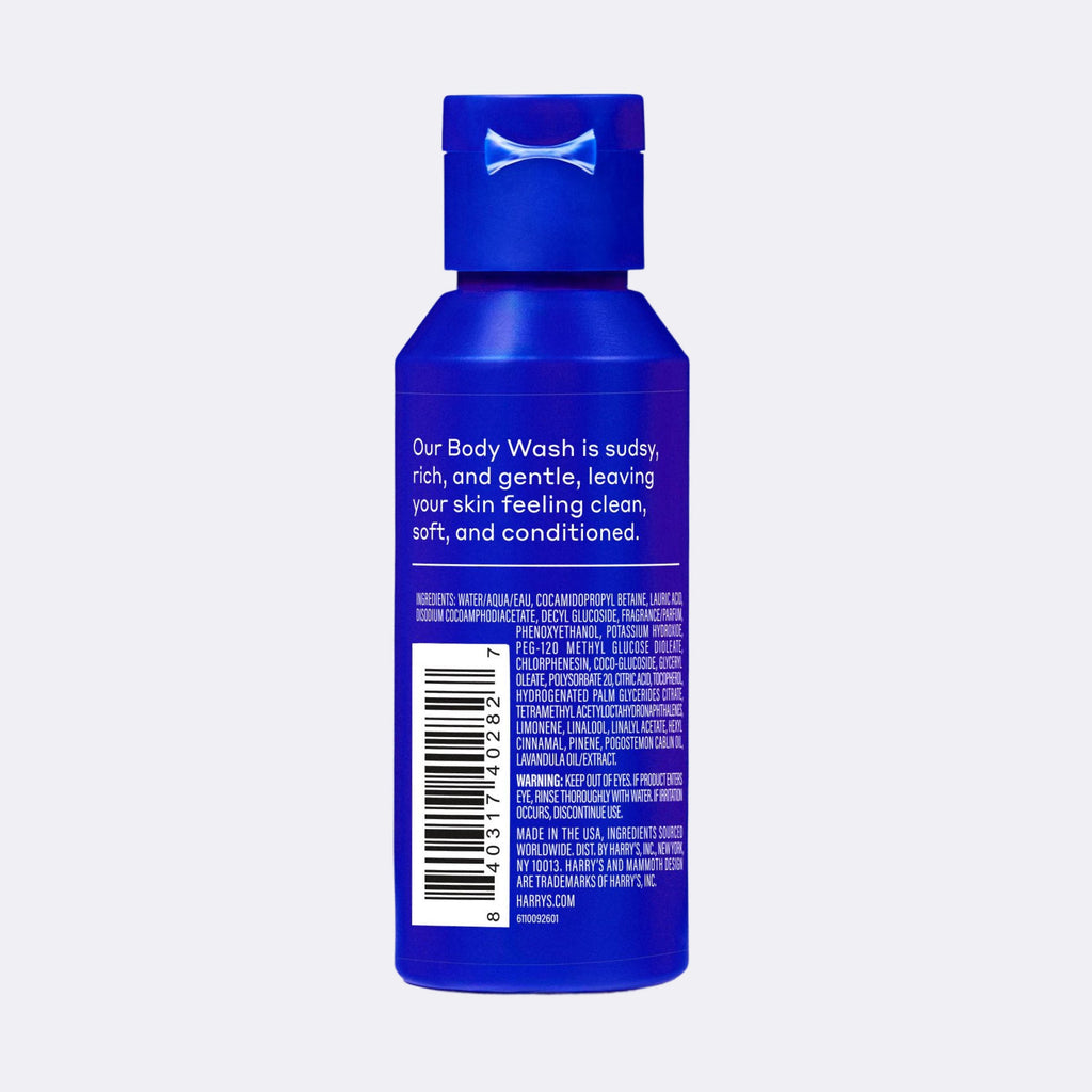The back of a small blue plastic bottle of body wash with a matching blue cap, featuring white text and a barcode on a light gray background.
