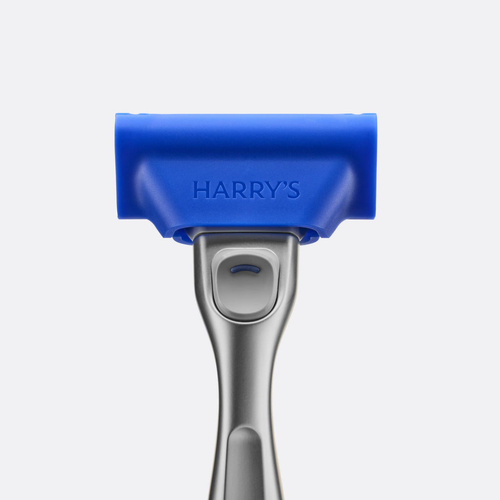 Blue and silver hair removal tool with 'HARRY'S' branding on a light gray background