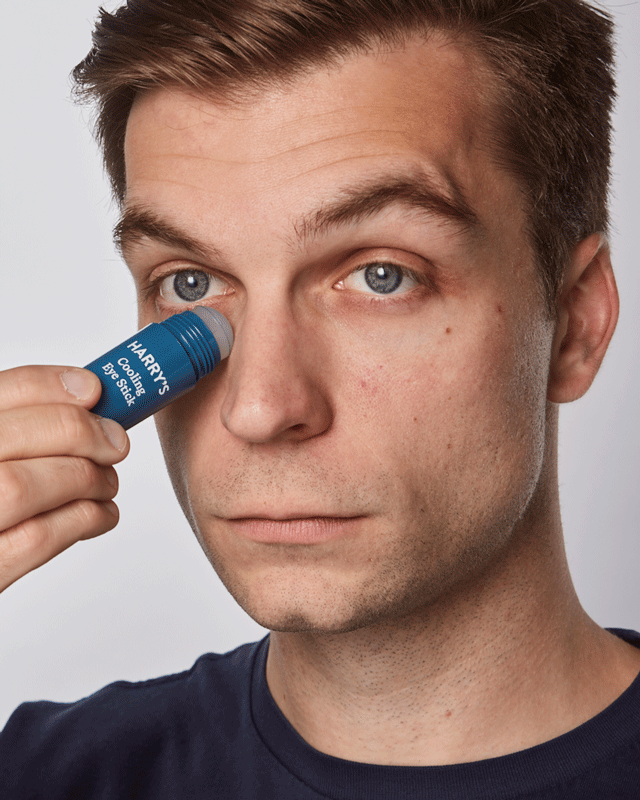 Man using cooling eye stick roller applicator under his eye
