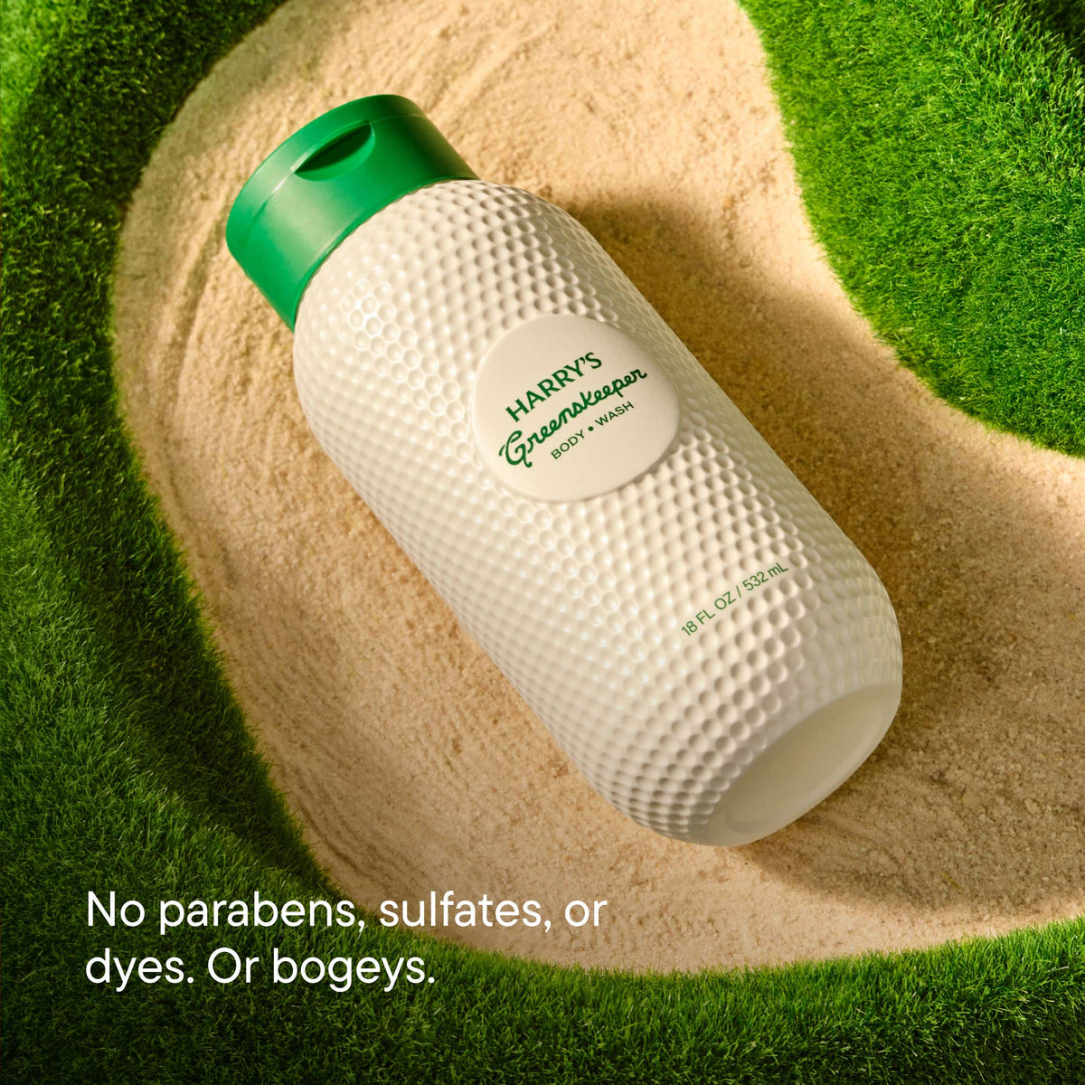 White textured bottle with green cap on a sand and grass background, featuring Harry's Greenbeard branding.