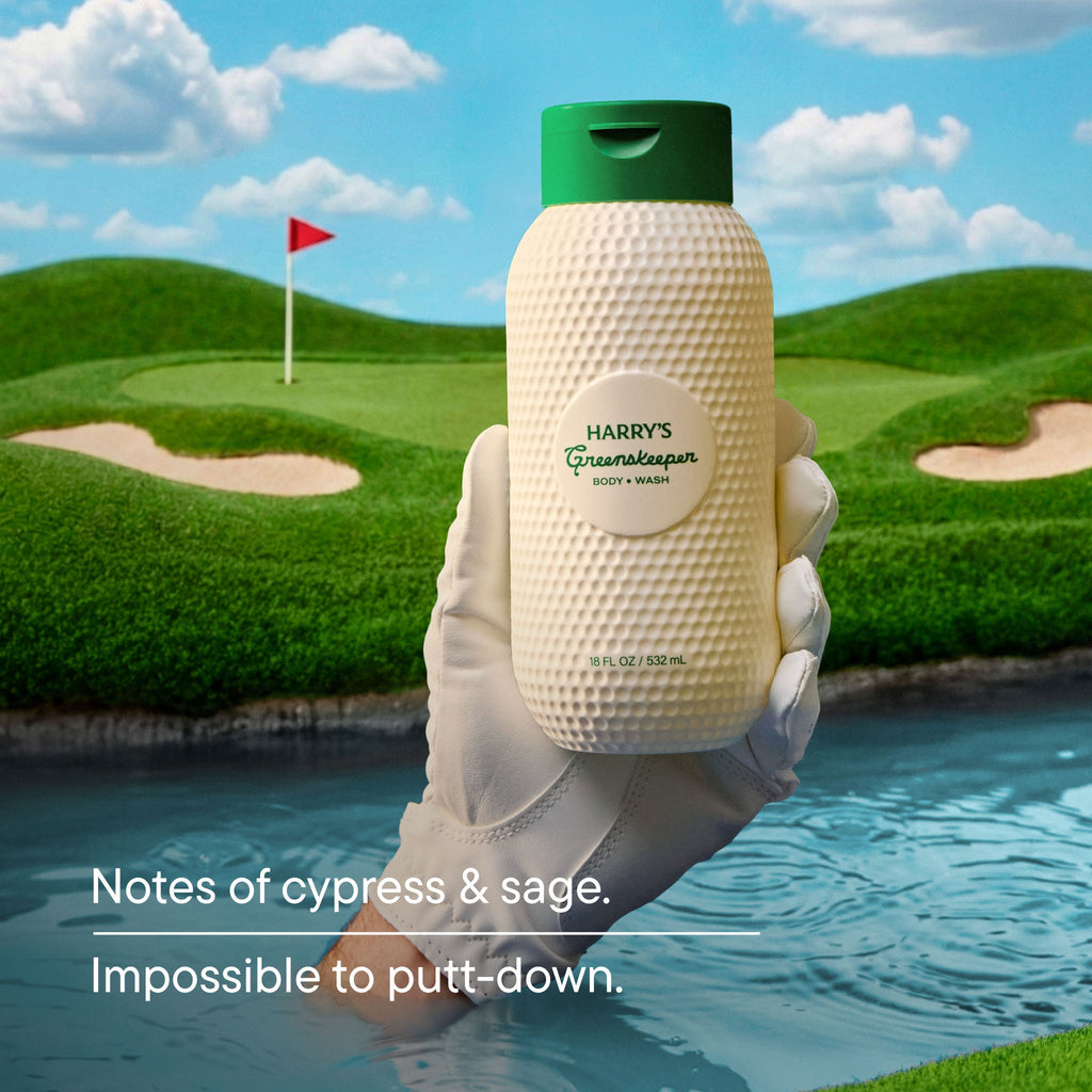 Hand holding a bottle of Harry's Greenskeeper product with a golf course background