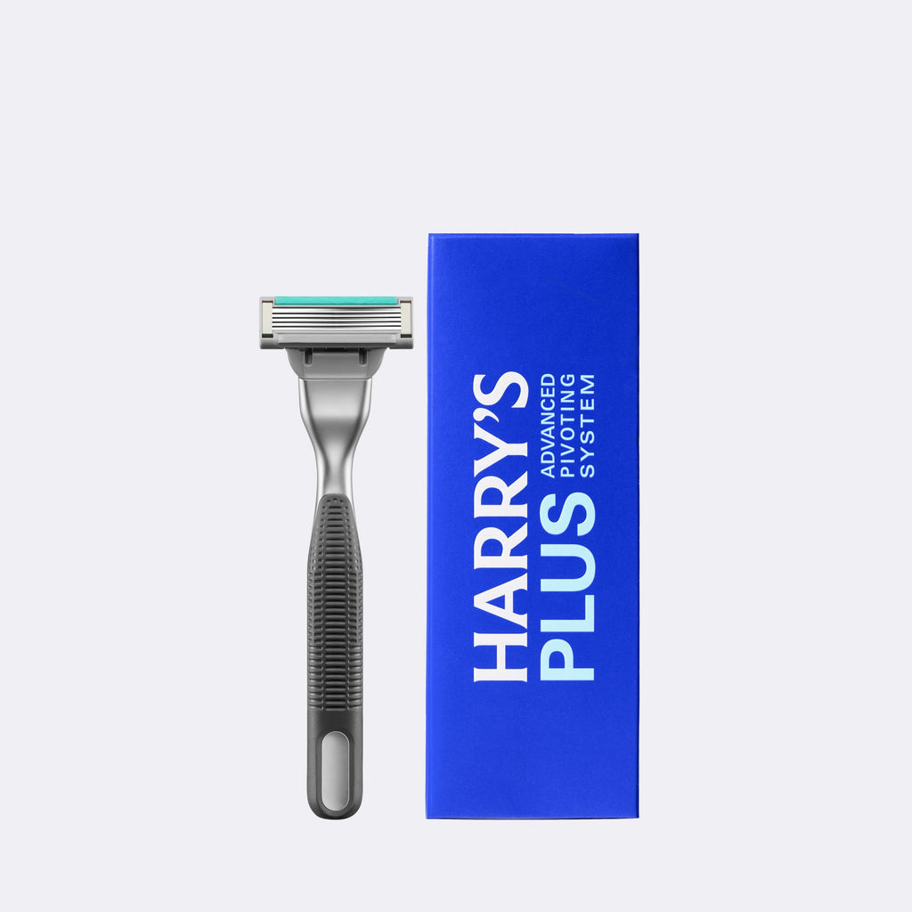 A single-handle shaving razor with a metallic silver head and textured dark gray handle, shown next to its bright blue packaging box featuring the text 'HARRY'S PLUS ADVANCED SYSTEM'.