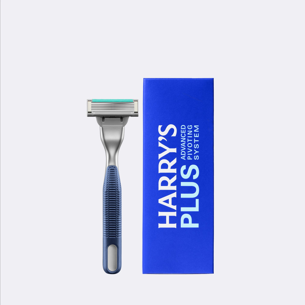 A single-sided men's razor with a blue and gray textured handle stands next to its blue packaging box, which features the text 'HARRY'S PLUS ADVANCED SYSTEM'. The background is a clean, solid light gray.