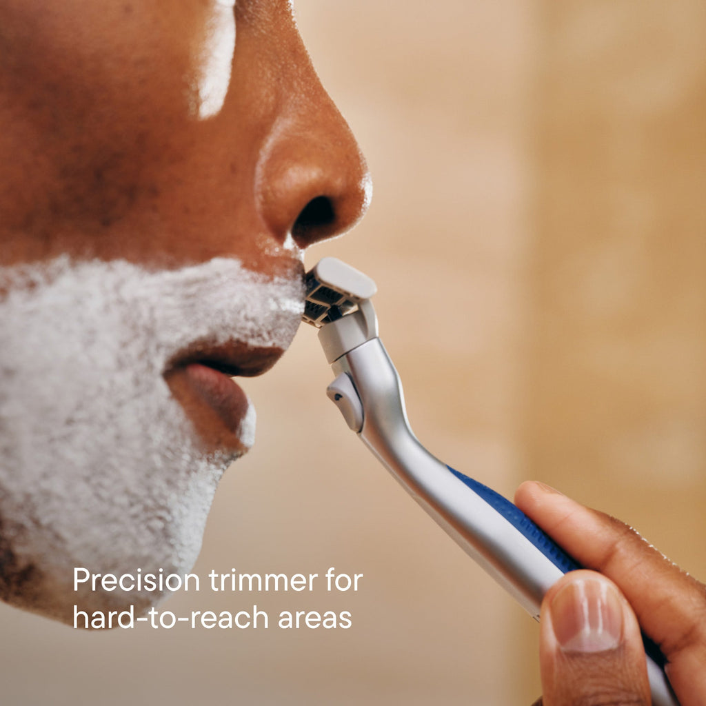 Person using a precision trimmer on their face with a blurred background