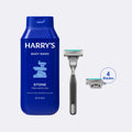 Blue bottle of Harry's body wash with a silver razor and four blades on a light gray background