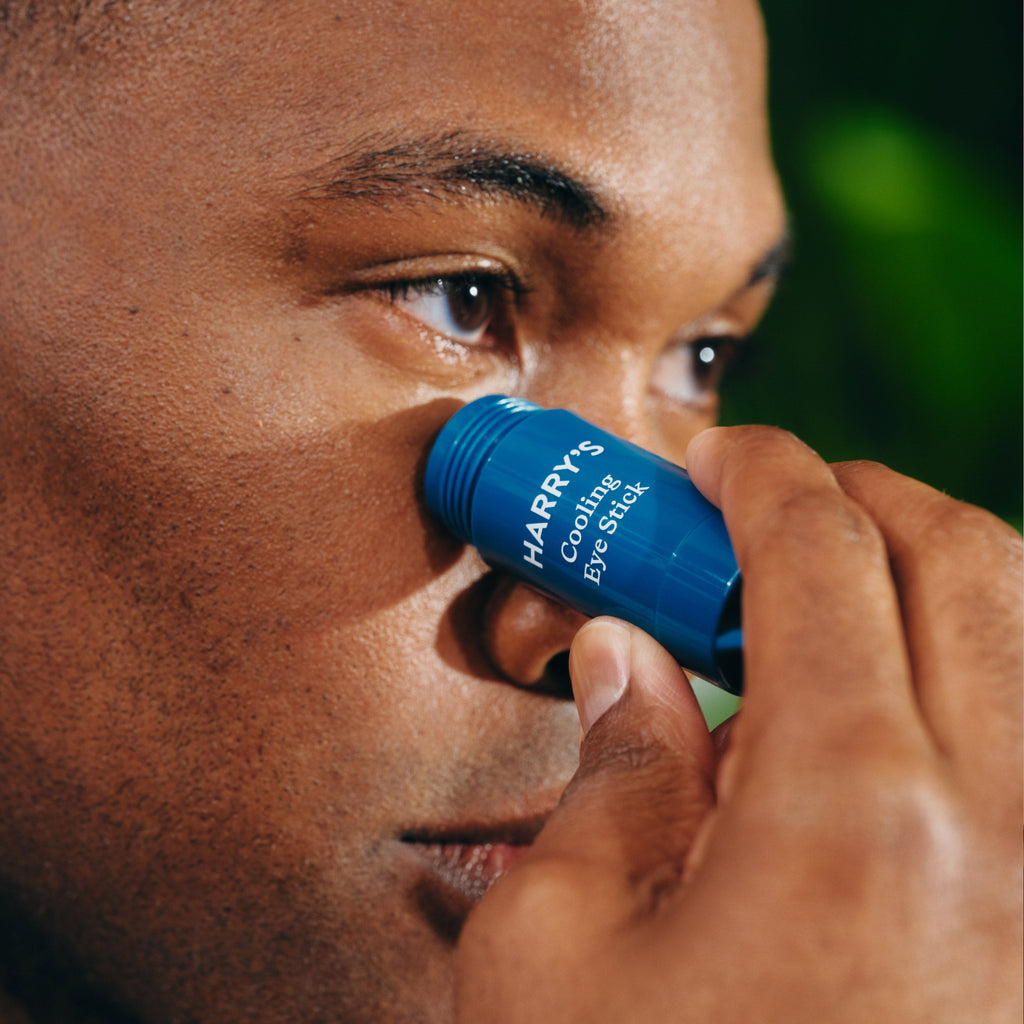Person applying a blue Harry's cooling eye stick to their eye.