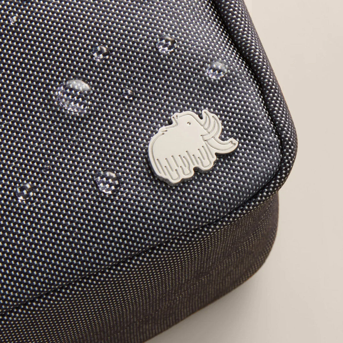 Detail of the enamel Harry's Mammoth logo on the corner of the Toiletry bag.