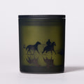 Candle with horse design on a black lid and base.