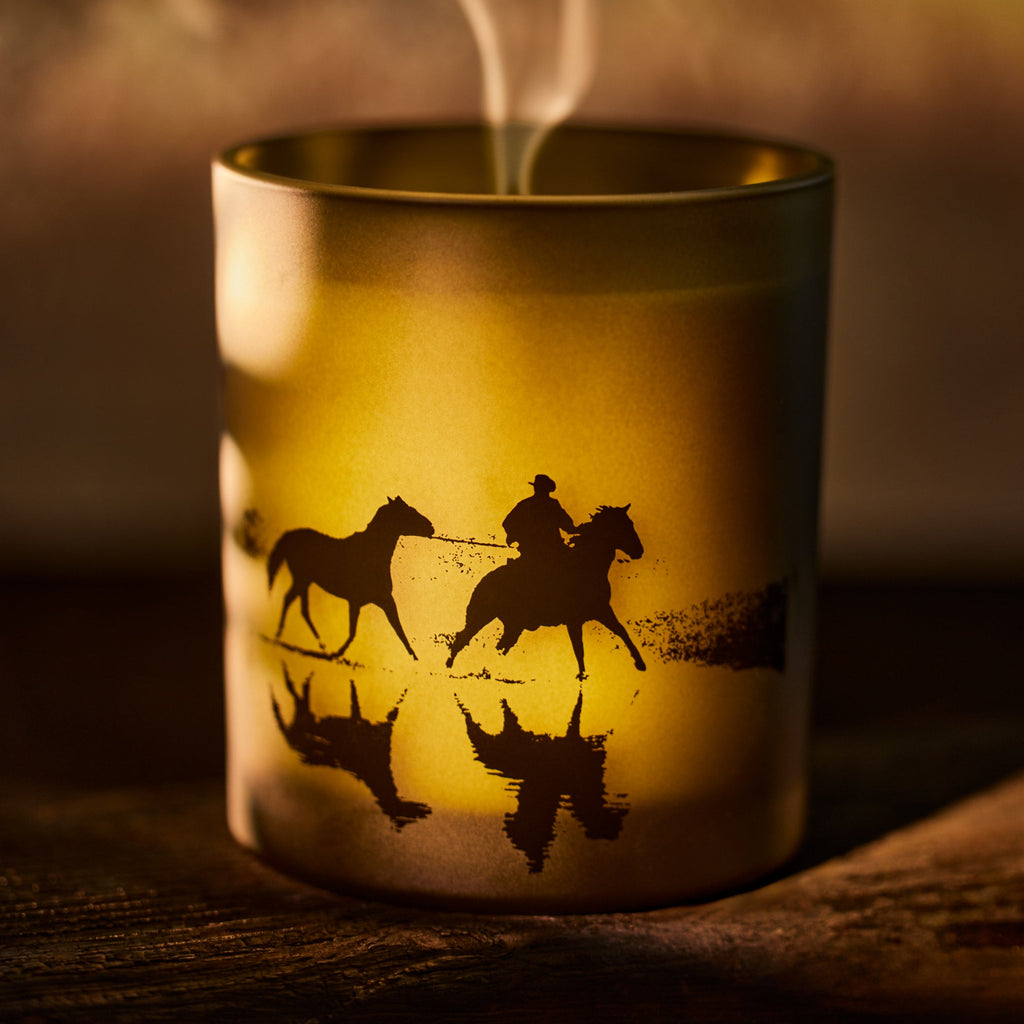 Candle in a holder with horse and rider design in warm lighting