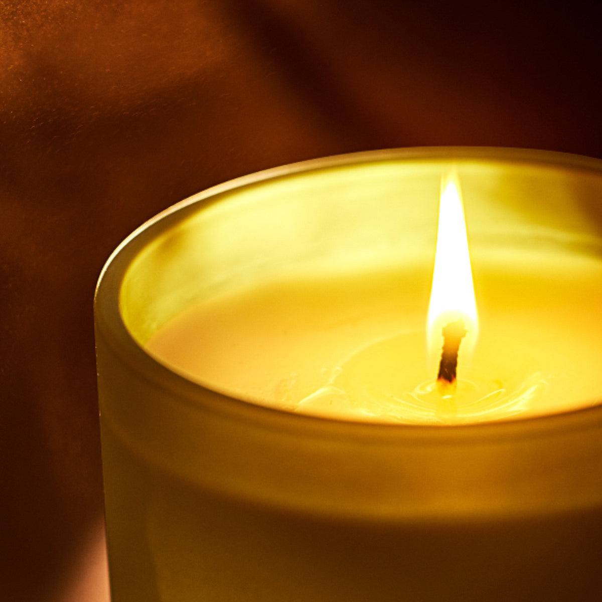 Candle with a burning flame against a dark background