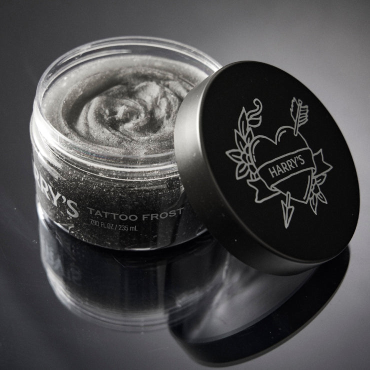 Jar of tattoo frost with 'Harry's' branding on a reflective surface