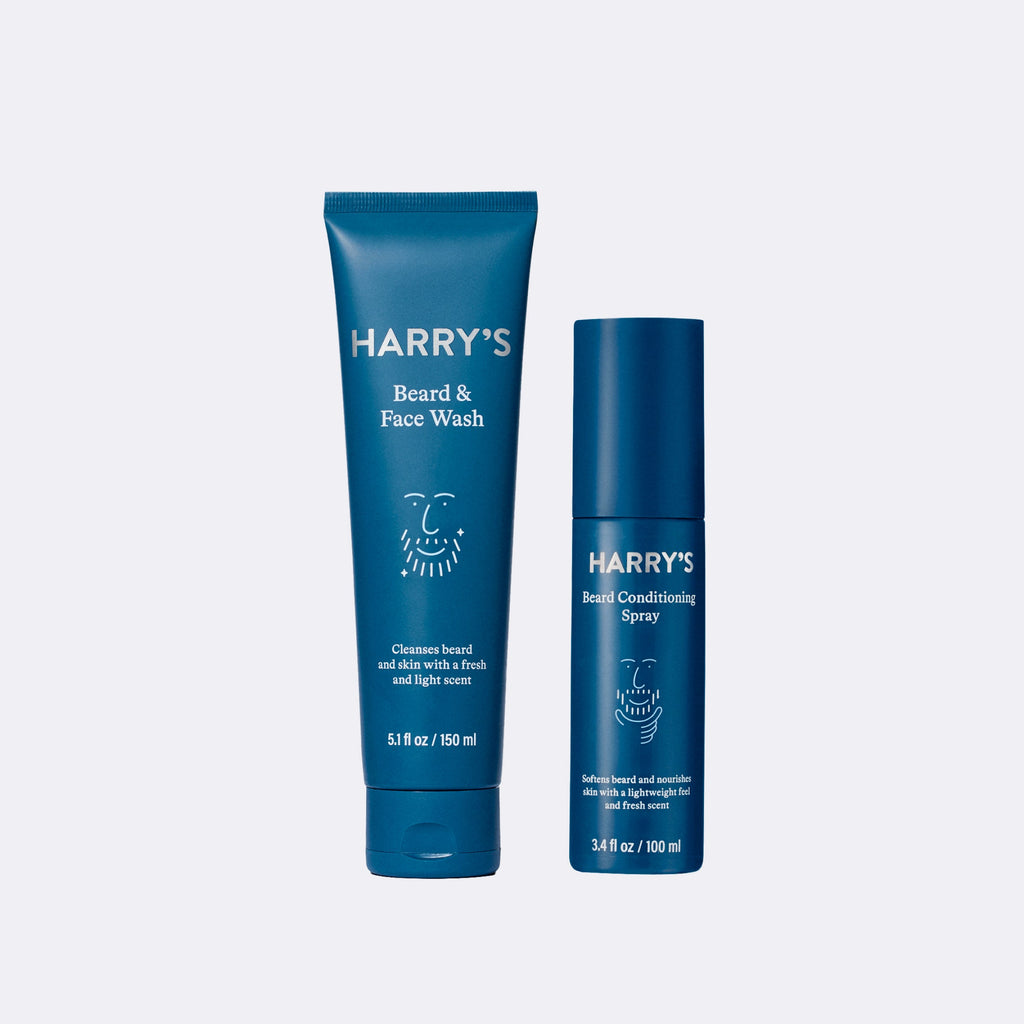 Two blue bottles of 'Harry's' beard and face wash and conditioning spray on a light gray background