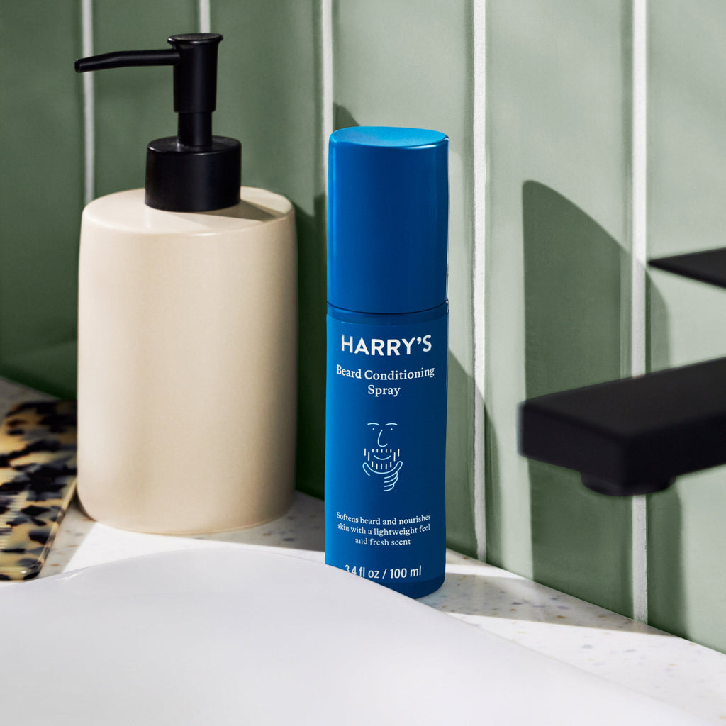 Blue bottle of 'Harry's' beard conditioning spray on a bathroom counter.