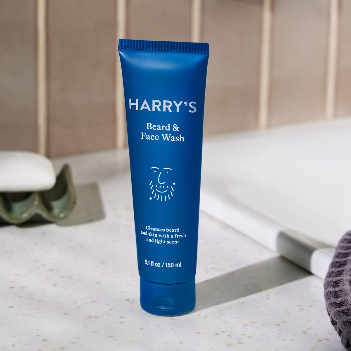 Blue tube of 'HARRY'S Beard & Face Wash' on a bathroom counter.