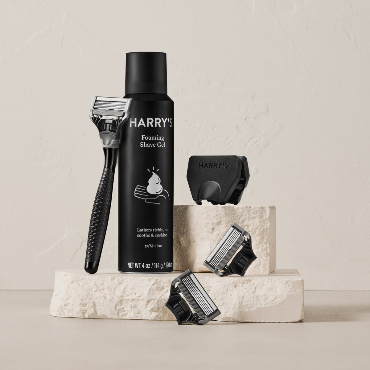 Harry's shaving product set including a bottle of shave gel, razor, and shaver head on a neutral background