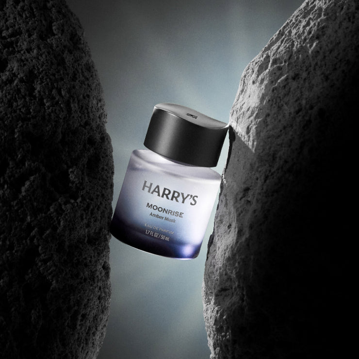 Harry's Moonrise cologne bottle between two rocks on a gradient background